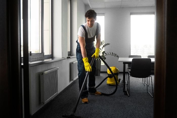Man meticulously cleans a room, ensuring a smooth transition with professional cleaning services.