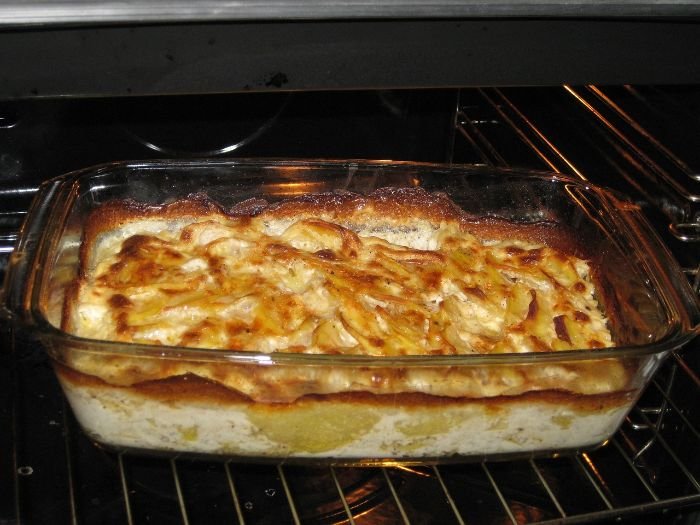 A homemade lasagna bakes to golden perfection in a clear glass dish inside an oven, highlighting the common challenge of cleaning up after such hearty, baked-in meals.