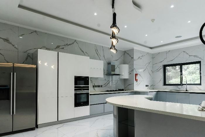 A pristine luxury kitchen with marble details and contemporary appliances, exemplifying the specialized cleaning solutions required for high-end home maintenance.