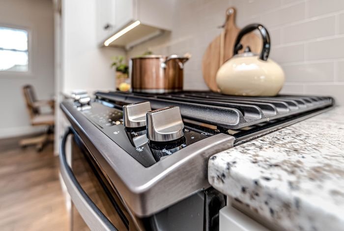A close-up view of a spotless kitchen stove top, highlighting the gleaming dials and grates, indicative of meticulous cleaning with specialized supplies for kitchen appliances.