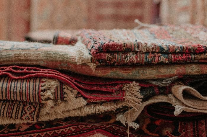A pile of intricately patterned oriental carpets, showcasing the variety and detail that may require specialized stain removal techniques.