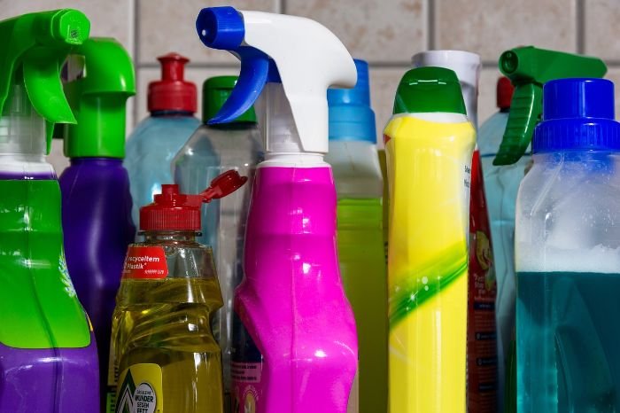 A collection of colorful cleaning supply bottles equipped with spray nozzles, lined up and ready for use in a DIY tenancy cleaning process.