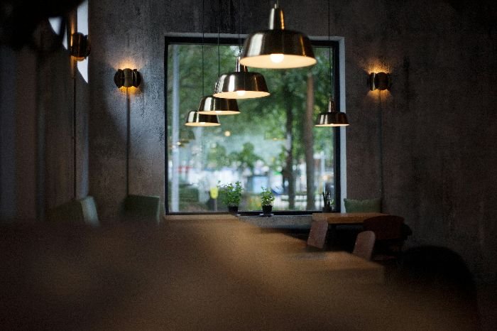 Stylish pendant lights reflecting in a mirror, illustrating the meticulous care needed when cleaning different materials of light fixtures.