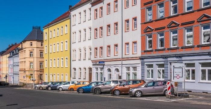 Brightly colored townhouses along a street with parked cars, symbolizing the residential areas where professional cleaning services are essential for maintaining rental property standards.