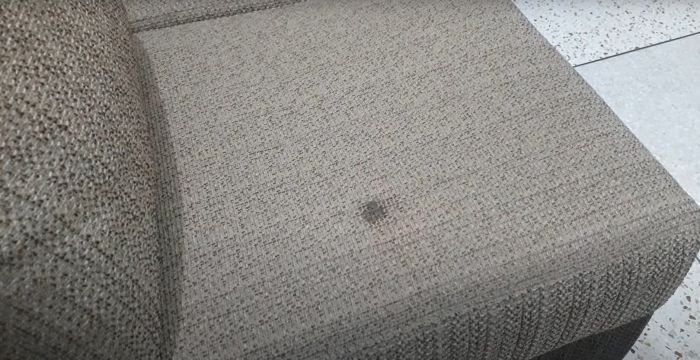 A close-up view of a subtle stain on the fabric of a two-toned upholstered chair, highlighting a common household cleaning challenge.