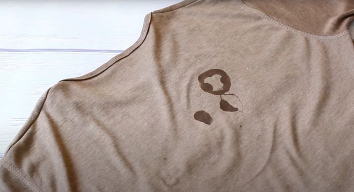 An oil stain forming a pattern on a light brown cotton shirt, underscoring the urgency of addressing fabric stains swiftly.
