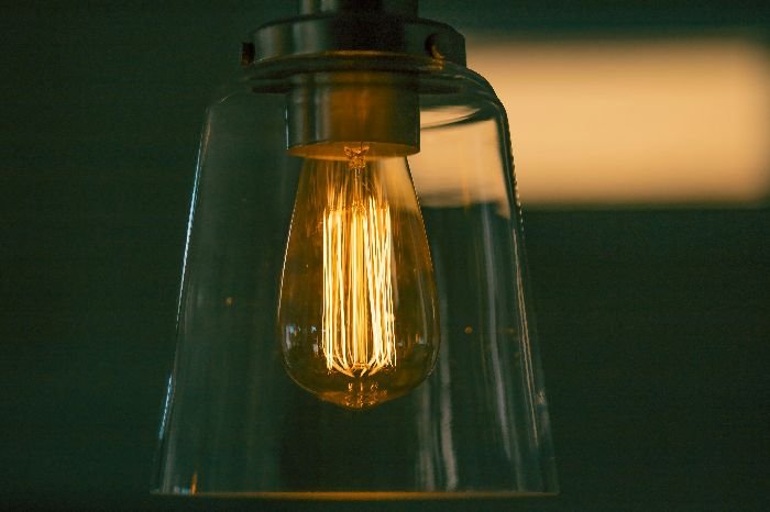 A warmly lit Edison bulb within a clear glass shade, exemplifying the type of light fixture being prepared for cleaning.