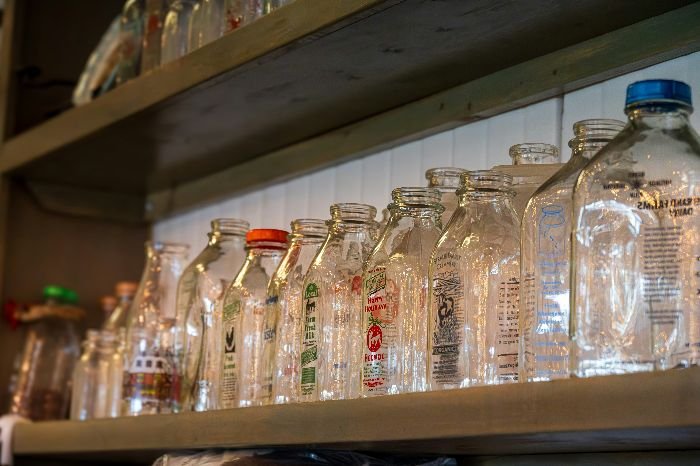 A neat array of empty glass jars on a wooden shelf, demonstrating the potential for repurposing them into sustainable storage containers for homemade cleaning products.