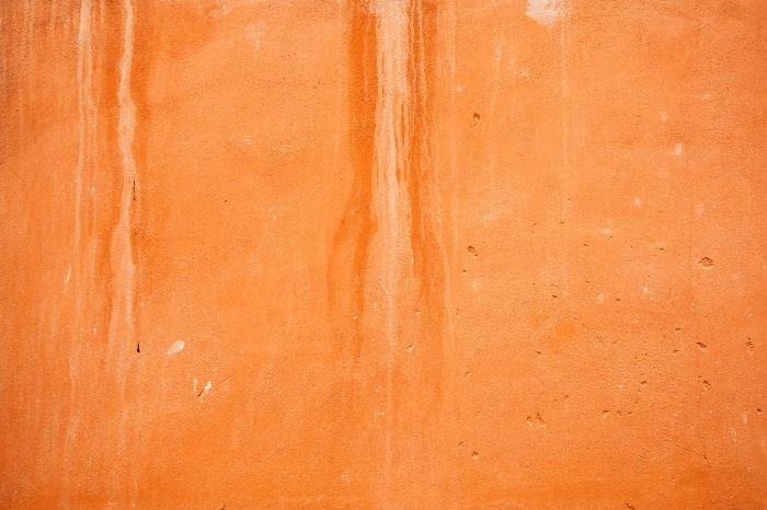 Streaks of water damage visible on an orange wall, representing the importance of identifying and addressing the source of water stains.